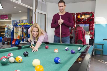 Man and woman playing billiards at holiday park Roompot De Soeten Haert