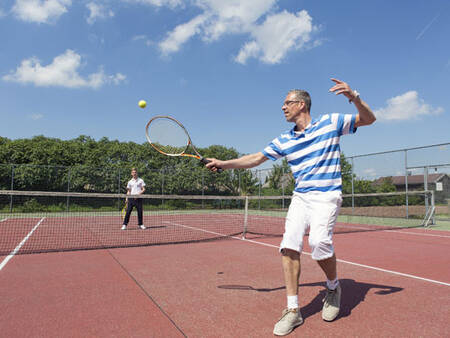 2 people play tennis on the tennis court of the Roompot De Veluwse Hoevegaerde holiday park