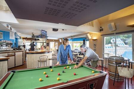 A couple is playing billiards at the Roompot Deux Fontaines holiday park