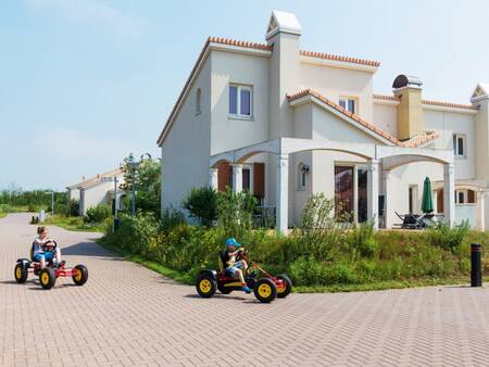 Children on go-karts and a house with a Mediterranean look at Roompot Duinresort Dunimar