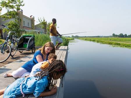 People fishing at holiday homes on the water at the Roompot Duinresort Dunimar . holiday park