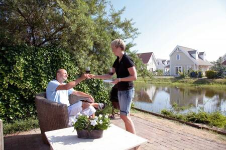 People in the garden by the water of a holiday home at Roompot Duynparc De Heeren van 's-Gravensande