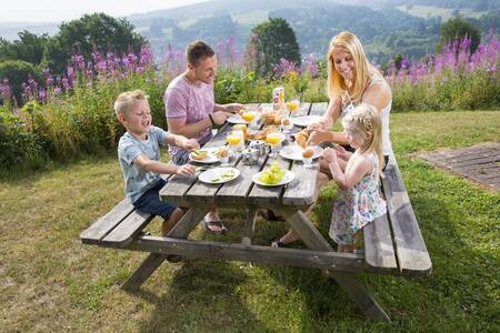People at a picnic table in the garden of a holiday home at Roompot Eifelpark Kronenburger See