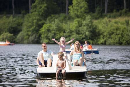 A family on a pedal boat on the lake next to Roompot Eifelpark Kronenburger See