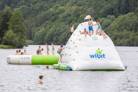 Children play on a play cushion in the reservoir next to Roompot Eifelpark Kronenburger See