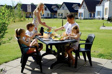 Family eats on the terrace of a holiday home at Roompot Ferienresort Cochem