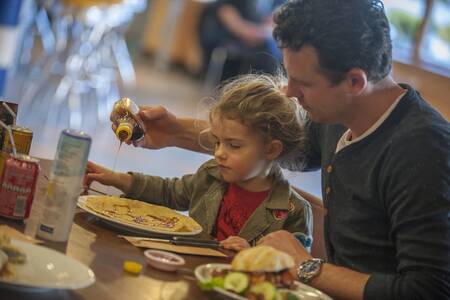 Family eats pancakes in a restaurant at Roompot Holiday Park Aquadelta