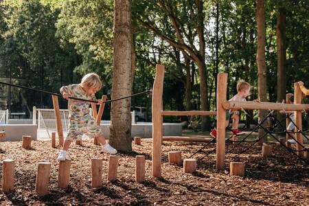 Children on wooden play equipment in a playground at Roompot Vakantiepark Kijkduin