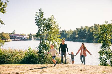 A family walks on the beach of the recreational lake at Roompot Vakantiepark Weerterbergen