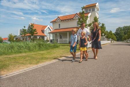 Family walks in front of a holiday home at Roompot Holiday Park Aquadelta