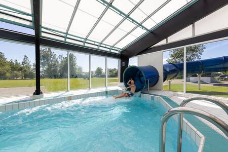 Boy on the big slide in the indoor pool of Roompot Holiday Park Callassande