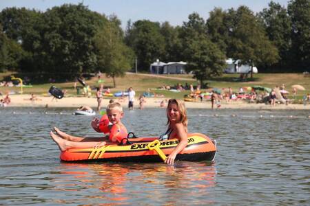 Woman with child in a rubber boat on the recreational lake of Roompot Holiday Park Hunzedal