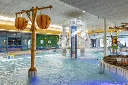 The indoor pool with water play equipment at Roompot Holiday Park Hunzedal