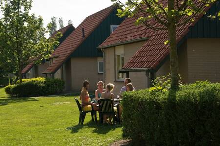People are sitting in the garden of a holiday home at holiday park Roompot Kustpark Klein Poelland