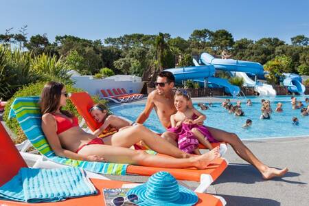 Family on sun loungers next to the outdoor swimming pool of the Roompot Le Littoral holiday park