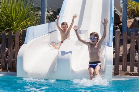 2 children slide down a double slide in the outdoor pool of the Roompot Le Littoral holiday park