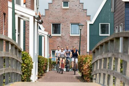 Family cycles between the holiday homes to a bridge at the Roompot Marinapark Volendam holiday park
