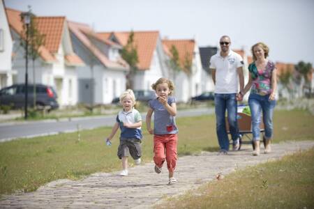 Family walks past holiday homes at Roompot North Sea holiday park Résidence Cadzand-Bad