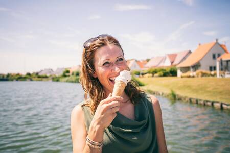 Woman eats an ice cream in front of holiday homes at Roompot Noordzee Résidence Cadzand-Bad