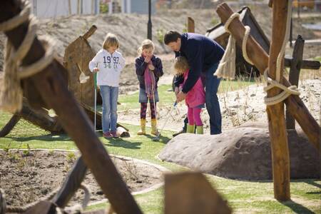 Family plays golf on the mini golf course at the Roompot Noordzee holiday park Résidence Cadzand-Bad