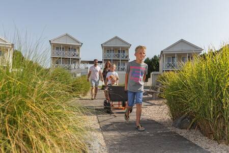 Family walks through marram grass at holiday homes at the Roompot North Sea Résidence De Banjaard