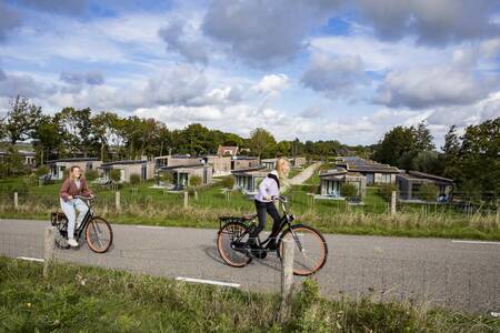 People cycle on the dike between the Roompot Park Wijdenes holiday park and the Markermeer