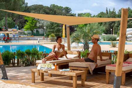 A couple on sunbeds by the outdoor pool of the Roompot Plein Air des Chênes holiday park
