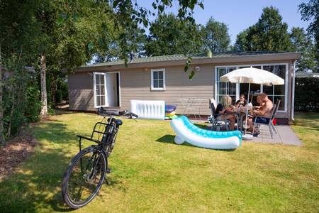 People at a table in the garden of a chalet at the Roompot Recreatiepark de Tolplas holiday park