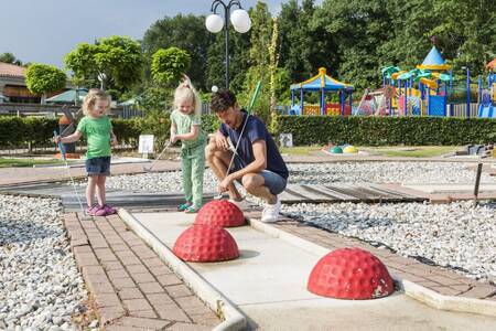 children together with their father on the mini golf course of the Roompot Resort Arcen holiday park