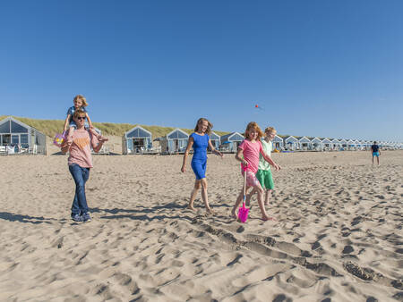 People walk on the beach in front of beach houses at Roompot Strandhuisjes Julianadorp