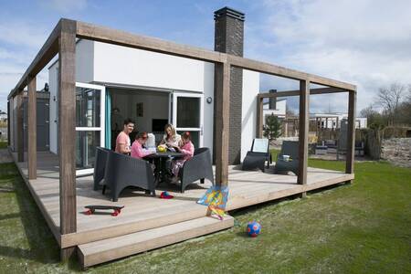 People on the veranda of a holiday home at the Roompot Strandpark Duynhille holiday park