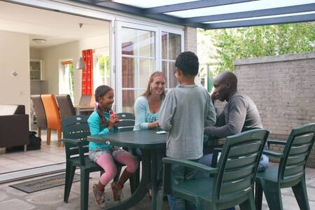 Family at the table under a roof at a holiday home at Roompot Holiday Park Hellendoorn