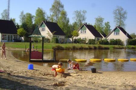 Children play on the beach of a recreational lake at Roompot Holiday Park Hellendoorn