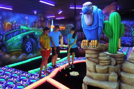 Family playing golf on the Glow in the dark mini golf course of Roompot Vakantiepark Weerterbergen