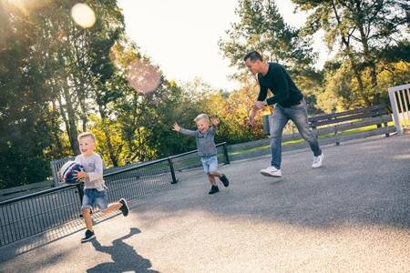 Father plays soccer with 2 children on a soccer field at Roompot Vakantiepark Weerterbergen