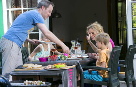 Family is eating in the garden of a holiday home at the Roompot Zeebad holiday park