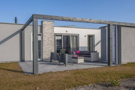 A lodge with garden furniture on the terrace at the Roompot Zeebad holiday park