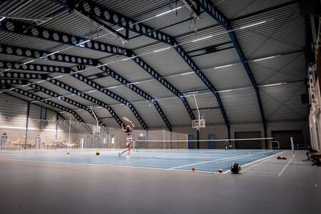 People playing tennis on the indoor tennis court of the Roompot Zeebad holiday park