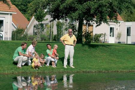 People fishing with holiday homes behind them at the Roompot Zeeland Village holiday park