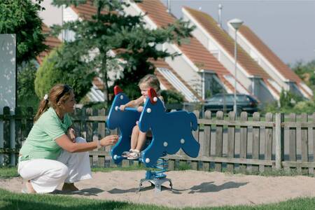 Mother with a child in the playground at the Roompot Zeeland Village holiday park
