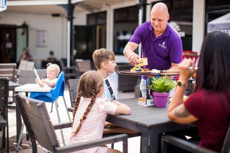 Family eating on the terrace of holiday park Topparken Bospark Ede