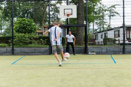 Boys play football on the sports field of the Topparken Bospark Ede holiday park