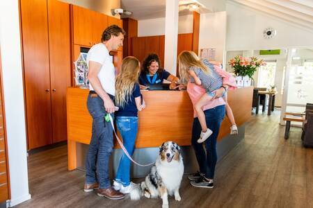 Family with dog at the reception of the Topparken Parc de IJsselhoeve holiday park