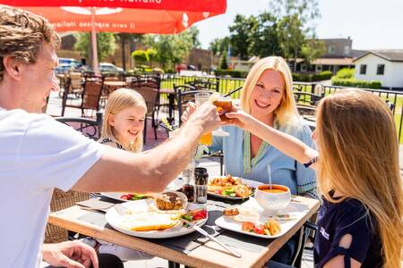 Family eating on the terrace of the restaurant at the Topparken Parc de IJsselhoeve holiday park