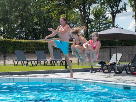 People jump into the outdoor pool of holiday park Topparken Recreatiepark de Wielerbaan