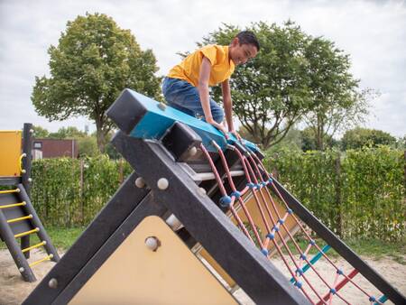 Boy climbs on a playground in a playground at Topparken Recreatiepark het Esmeer