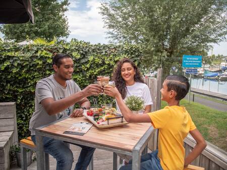 Family eating on the terrace of the restaurant at Topparken Recreatiepark het Esmeer