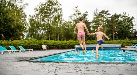 Two children jump into the outdoor pool of the Topparken Recreatiepark 't Gelloo