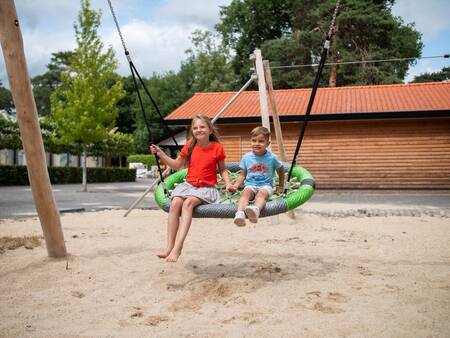 Children on a swing in the playground of the Topparken Resort Veluwe holiday park