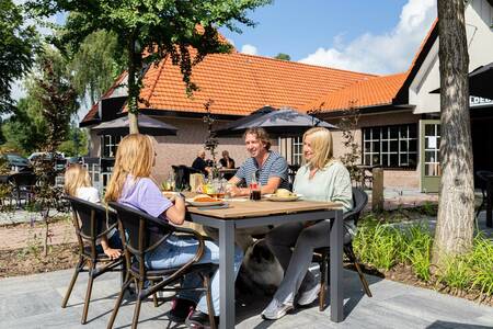 Family eating on the terrace of the restaurant of the Topparken Resort Veluwe holiday park
